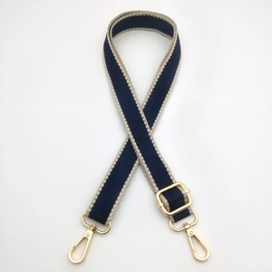 Close-up of adjustable dark blue bag strap with gold metal hooks and geometric patterns