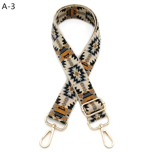 Detail of adjustable geometric jacquard bag strap with golden metal lobster clasps