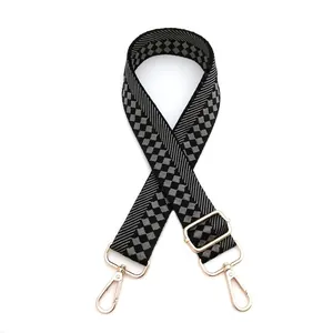 Close-up of black and grey checkered adjustable shoulder strap with gold swivel hooks