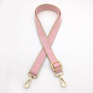 Detail of adjustable pink geometric jacquard bag strap with golden metal swivel hooks