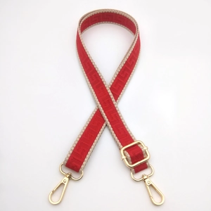 Detail of red geometric woven strap with gold metal hooks and adjustable buckle