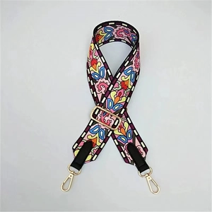 Detail of colorful floral woven bag strap with golden metal hooks and black leather ends