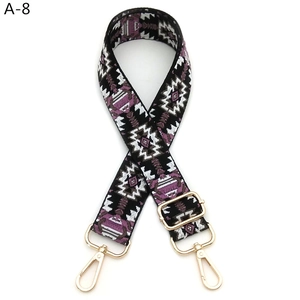 Detail of adjustable embroidered bag strap with floral jacquard pattern and golden hooks