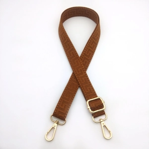 Close-up of caramel brown 2.5cm woven bag strap with geometric patterns and gold metal hooks