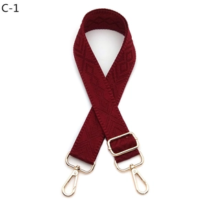 Detail of burgundy diamond pattern woven shoulder strap with gold metal swivel hooks