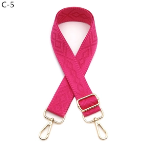 Detail view of pink diamond-patterned woven shoulder strap with gold metal buckles