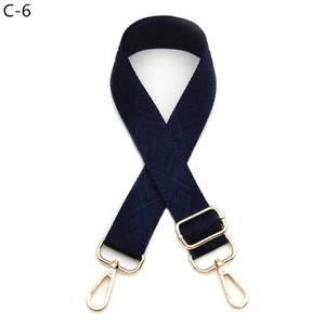 Detail of adjustable dark blue diamond pattern woven shoulder strap with gold metal hooks