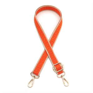Detail of orange adjustable woven bag strap with Greek meander pattern and gold metal clasps