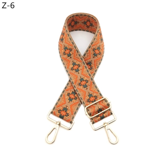 Close-up of woven ethnic geometric bag strap with orange green patterns and gold hooks