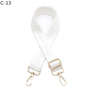 Detail of adjustable white woven bag strap with golden metal hardware and embroidery
