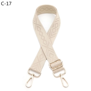 Close-up of adjustable beige jacquard bag strap with gold metal hooks and diamond pattern