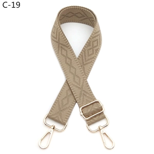 Close-up of adjustable khaki embroidered strap with geometric rhombus pattern and gold metal hooks