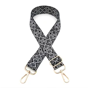Close-up of black and white geometric canvas bag strap with golden metal hooks