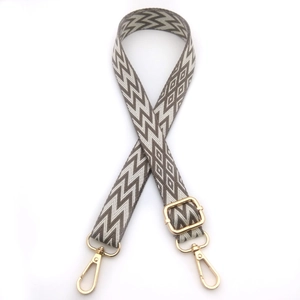 Detail of adjustable gray and beige chevron woven strap with golden lobster clasps