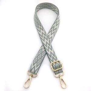 Detail of adjustable gray-white geometric wave pattern bag strap with gold metal hooks