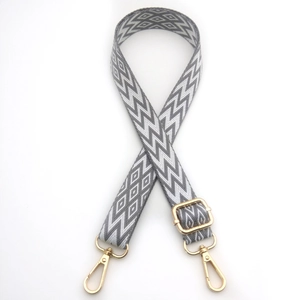 Detail of adjustable bag strap with grey and white geometric pattern and gold hardware