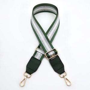 Detail of adjustable green fabric bag strap with silver glitter stripes and gold hardware