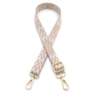 Detail of adjustable woven bag strap with pink geometric pattern and gold-tone metal clips