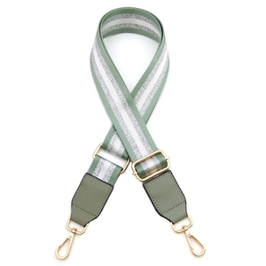 Detail of adjustable green and silver striped woven shoulder strap with gold lobster clasps