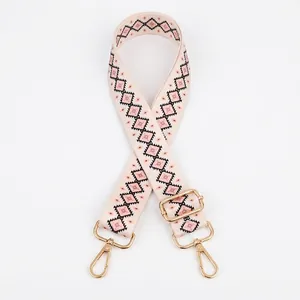 Detail view of pink geometric ethnic strap with adjustable gold metal buckle for bags