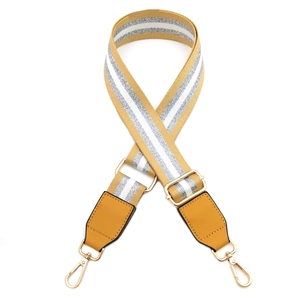 Detail of adjustable ginger and white striped fabric bag strap with golden metal hooks