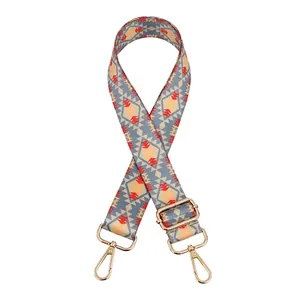 Detail of bohemian style adjustable bag strap with ethnic geometric patterns and gold buckle