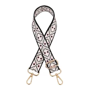 Close-up of adjustable white shoulder strap with black geometric pattern and gold hooks