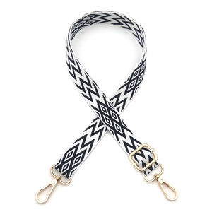 Close-up of geometric black and white woven bag strap with golden metal swivel hooks