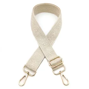 Detail of ethnic style beige woven bag strap with golden metal snap hooks and adjuster