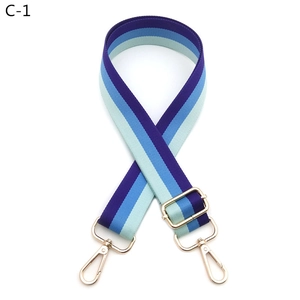 Detail of adjustable blue striped bag strap with gold metal rotating hooks and slider