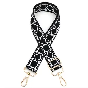 Detail of adjustable black and white geometric diamond pattern strap with gold metal hardware
