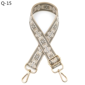 Close-up of ethnic embroidered bag strap with floral patterns and gold metal buckles