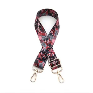 Detail of wide woven strap with red floral patterns and gold metal lobster clasps
