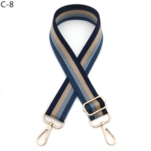 Detail of adjustable wide striped canvas bag strap with golden metal snap hooks