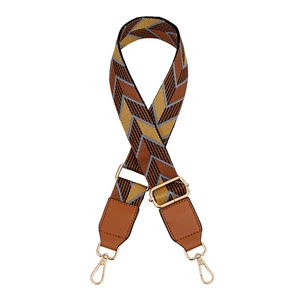 Detail of adjustable wide woven bag strap with colorful chevron pattern and gold metal hooks