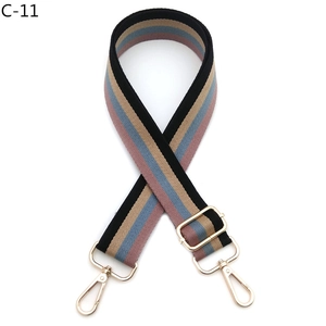 Detail of adjustable colorful striped canvas bag strap with pale gold metal hardware hooks