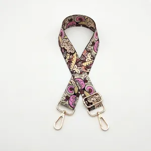 Close-up of adjustable woven bag strap with colorful vintage swirl floral pattern and gold hooks