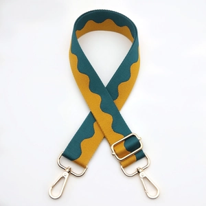 Detail of adjustable wide shoulder strap with green wave pattern and gold metal hooks