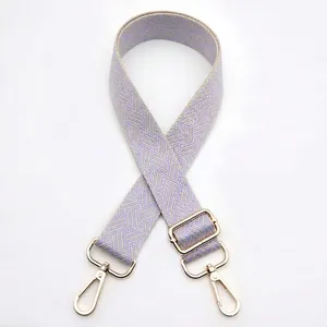Detail of light purple woven bag strap with golden metal buckles and geometric pattern