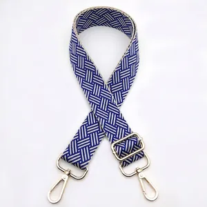 Detail of blue and beige woven bag strap with adjustable gold lobster clasps
