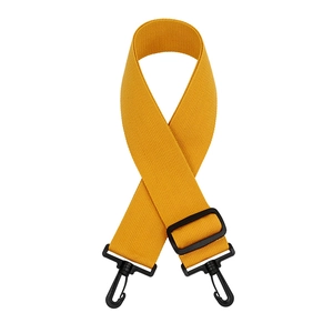 Detail view of mustard yellow adjustable canvas bag strap with black plastic swivel hooks