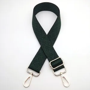 Detail of adjustable woven bag strap in dark green and black with gold lobster clasps