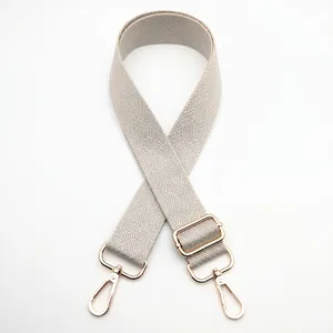 Detail of adjustable woven grey and white shoulder strap with gold metal lobster clasps