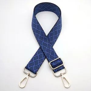 Detail of navy blue woven bag strap with adjustable gold buckle and swivel metal hooks