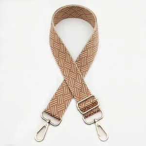 Detail of adjustable coffee and beige woven bag strap with golden metal swivel hooks