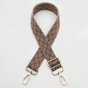 Detailed view of woven geometric bag strap with premium gold metal lobster clasps