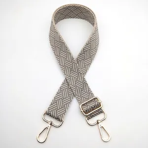 Close-up of woven herringbone shoulder strap with adjustable gold metal lobster clasps