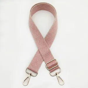 Close-up of pink and beige woven herringbone shoulder strap with gold swivel hooks