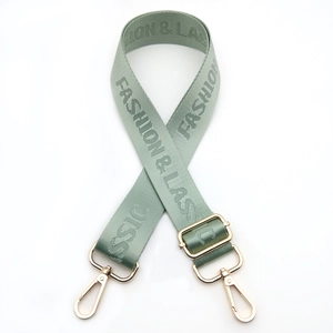 Detail of adjustable nylon bag strap in sage green with golden lobster clasps