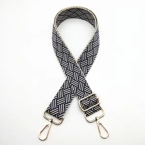 Detail of blue and white geometric jacquard bag strap with gold metal hooks and buckle